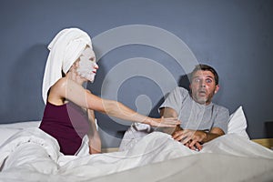 Funny lifestyle portrait of man and woman featuring weird married couple with wife in head towel and makeup face mask demanding se photo