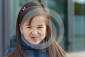 Funny little Asian girl wrinkling up her nose