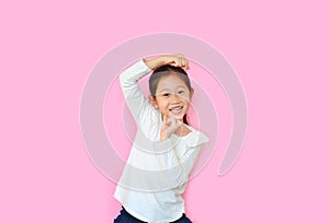 Funny little asian kid girl with expression monkey face and hands isolated on pink background. Amusing playful child monkeying photo