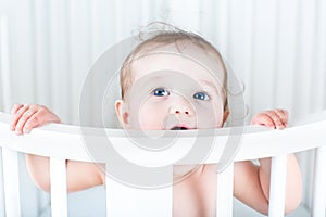 Funny little baby with beautiful blue eyes in crib