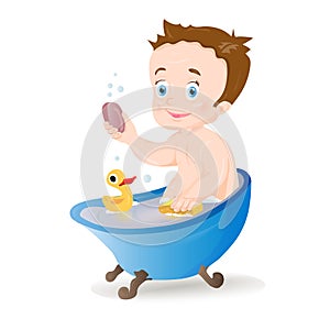 Funny little baby boy with soap in the basin and playing with a yellow rubber duck toy.