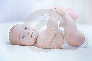 Funny little baby boy wearing a diaper playing in a sunny nurser