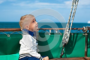 Funny little baby captain on board of sailing yacht