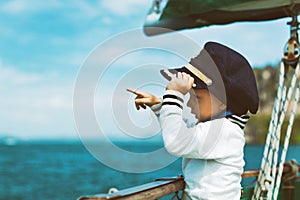 Funny little baby captain on board of sailing yacht