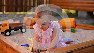 Funny little baby girl playing with sand on a playground