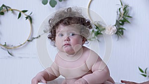 Funny little baby girl posing on photo session in studio on background of white wall with decor