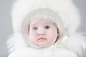 Funny little baby girl wearing a huge fur hat