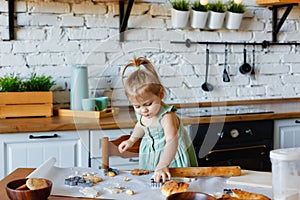 Funny little baby helper playing with dough learning to knead helps mom in the kitchen, happy cute baby daughter