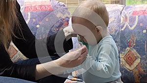 Funny little baby trying to destroy disposable protective face mask