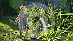 Funny little boy 1.5 years studying hosing plants in the garden