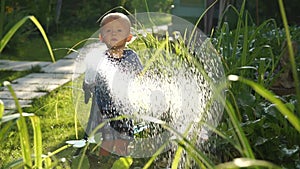 Funny little boy 1.5 years studying hosing plants in the garden