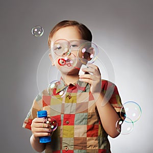 Funny little boy blowing soap bubbles.happy child