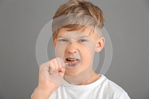 Funny little boy eating lollipop on grey background