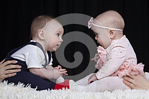 Funny little boy and girl are sitting opposite each other