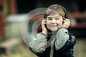 Funny little boy in headphones, outdoors. Happy.
