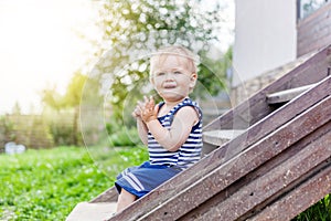 Funny little boy one year, sitting on the porch of a country house. Summer, childhood, nature