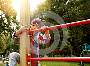 Funny little boy on playground. Cute boy play and climb outdoors on sunny summer day.