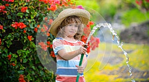 Funny little boy playing with garden hose in backyard. Child having fun with spray of water on yard nature background