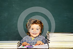 Funny little boy pointing up on blackboard. Little student boy happy with an excellent mark. Classroom. Kids school