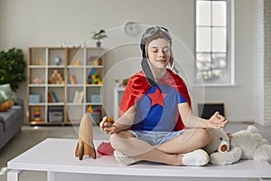 Funny little boy sitting on the table in the lotus position in the nursery.