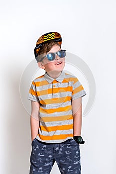 Funny little boy in sunglasses express surprised face, isolated on white background. Kid in cap. Cool boy kidding