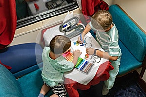 Funny little brothers travel by train riding at comfortable railway carriage drawing picture