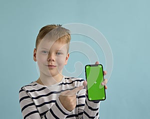 Funny little caucasian kid boy 9s years old in basic striped shirt hold mobile cell phone.