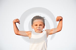 Funny little caucasian kid with grimace on his face showing biceps muscle