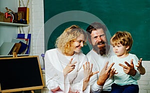 Funny little child with family having fun on blackboard background. Mother father and son together schooling. Happy