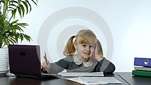 Funny little child girl boss manager emotionally talking on mobile phone, sitting at computer table