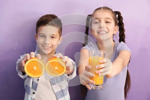 Funny little children with citrus fruit and juice on color background