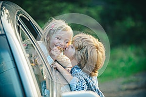 Funny little couple saying goodbye before car travel. Bye bye. Farewell concept. Little boy gives warm kiss. Goodbye