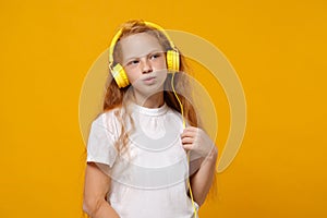 Funny little ginger kid girl 12-13 years old in white t-shirt isolated on yellow wall background children studio