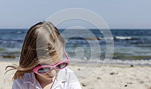 Funny little girl 7 years old in sunglasses lies on the beach