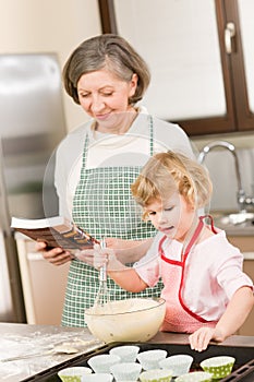 Funny little girl baking cupcake with grandma