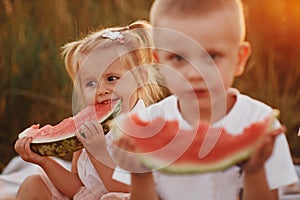 Funny little girl biting a slice of watermelon outdoors on warm and sunny summer day. happy childhood. selective focus