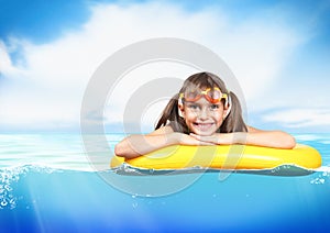 Funny little girl with diving glasses floating inflatable ring a