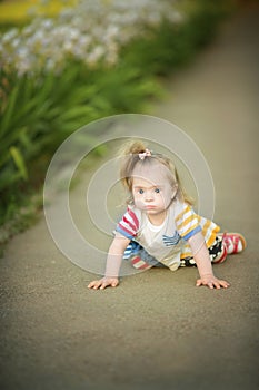 Funny little girl with Down syndrome creeps along the path photo