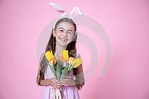 Funny little girl with easter bunny ears holding a bouquet of spring flowers copy space