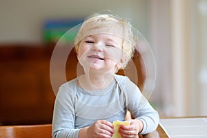 Funny little girl eating sandwich at home