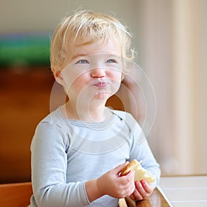 Funny little girl eating sandwich at home