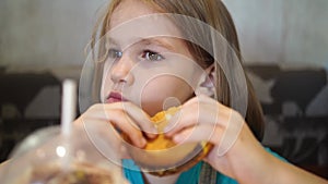 Funny little girl eats a burger in a cafe. fast food cafes.