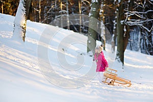 Funny little girl having fun with a sleight in beautiful winter park
