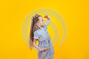 Funny little girl looking ahead on yellow background