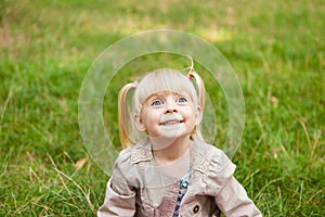 Funny little girl making faces outdoors in summer