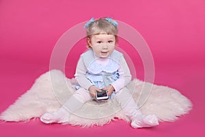 Funny little girl playing with mobile phone over pink background