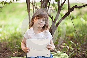 Funny little girl playing with tablet outdoors