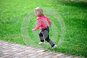 Funny little girl runing on green grass