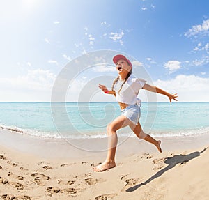 Funny little girl running and jumping on beach