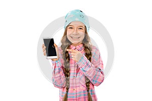 Funny little girl showing smart phone with blank screen on white background. Playing Games and watch video.